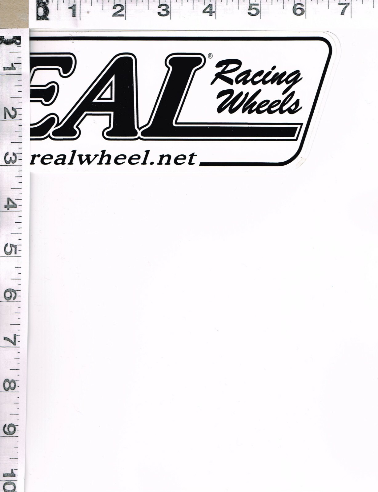 NEW, REAL RACING WHEELS STICKER, 11″ X 3″, BLACK WRITING ON WHITE BACKGROUND