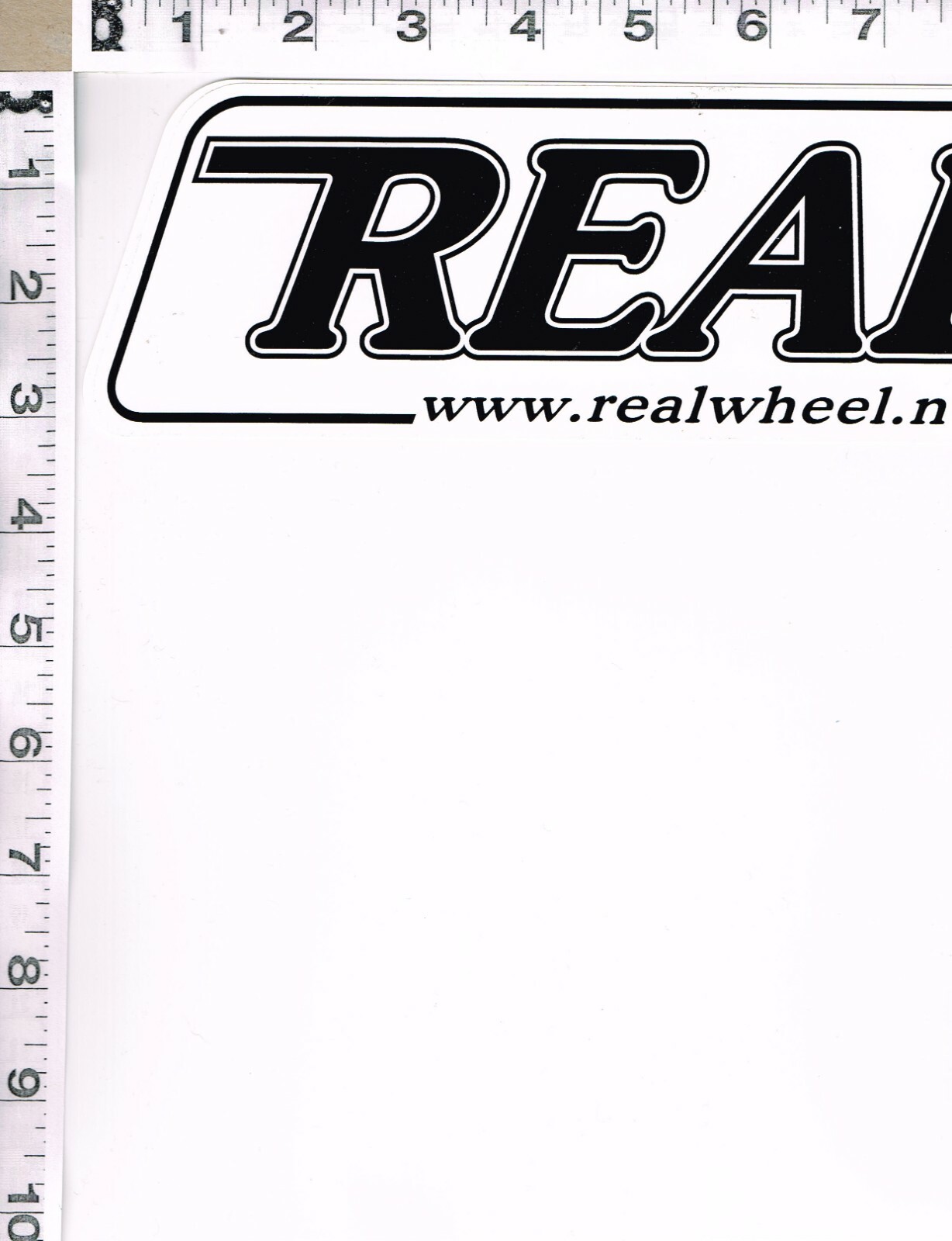 NEW, REAL RACING WHEELS STICKER, 11″ X 3″, BLACK WRITING ON WHITE BACKGROUND